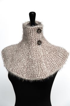 a mannequin wearing a white knitted cowl with buttons on the collar