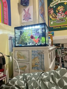 a fish tank sitting on top of a dresser in a room with posters above it