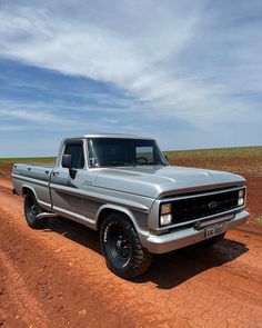 an old pickup truck parked on a dirt road