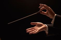 a conductor is holding his baton in the air