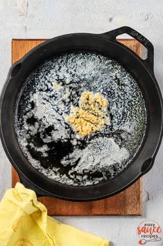 an iron skillet with powdered sugar in it on a wooden cutting board next to a yellow cloth