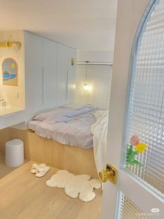 a bedroom with white walls and wooden flooring next to an open door that leads to a bathroom