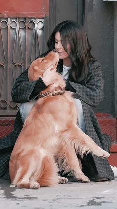 a woman is sitting on the ground with her dog and petting it's face