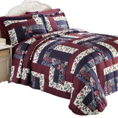 a bed with a red and blue quilted comforter set on top of it