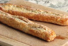 two long bread sticks sitting on top of a cutting board