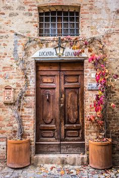 an old brick building with two large wooden doors and planters on the outside wall