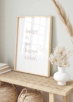 a white vase sitting on top of a wooden table next to a framed poster and some baskets