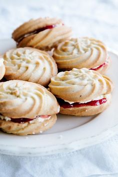 several cookies with jelly and cream filling on a white plate