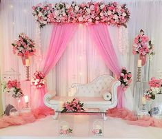 a white couch sitting under a pink canopy next to a table with flowers on it