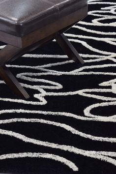 a black rug with white lines on it and a brown leather bench in the middle