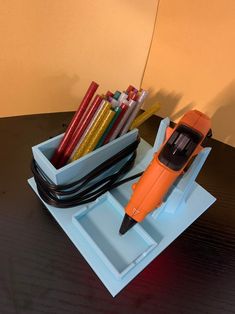 an orange and black hair dryer sitting on top of a table next to some pens