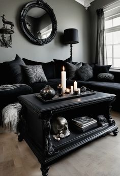 a living room filled with black furniture and candles in front of a mirror on the wall