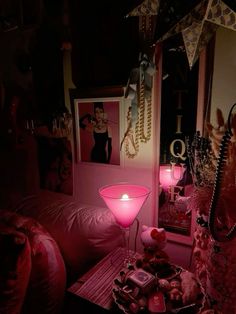 a living room with pink furniture and pictures on the wall, candles in glass vases