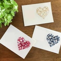 three cards with hearts on them sitting next to a potted plant