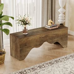 a wooden bench sitting on top of a hard wood floor next to a vase with flowers