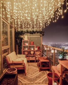 a room with lights hanging from the ceiling and furniture on the balcony, in front of a cityscape