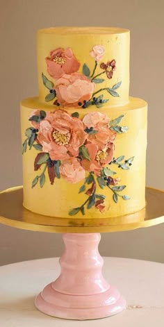 a yellow cake with pink flowers painted on it