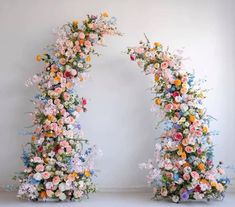 two archways with flowers on each side and white wall in the backround