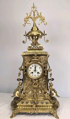 an ornate gold clock is sitting on a white surface