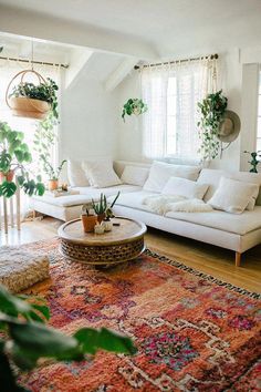 a living room with white couches and potted plants on the windowsills