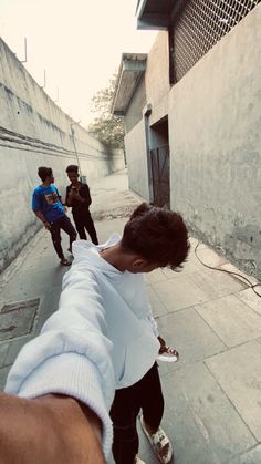 a person pointing at another person on a skateboard in an alley with other people