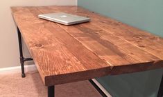 a laptop computer sitting on top of a wooden table next to a wall in a room