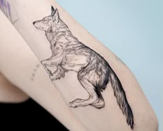 a woman's arm with a tattoo of a wolf on the left side of her body