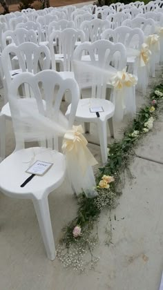 rows of white chairs with bows and flowers on them