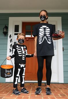 two children in skeleton costumes holding hands and standing next to each other on the front porch