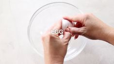 two hands holding an egg in front of the word egg on a clear plate with white background