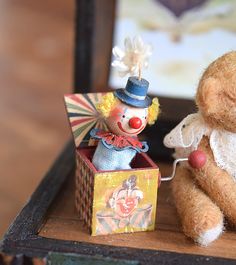 two small teddy bears sitting on top of a wooden table next to an open box