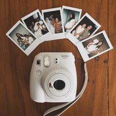 a polaroid camera sitting on top of a wooden table next to several pictures and a white cord