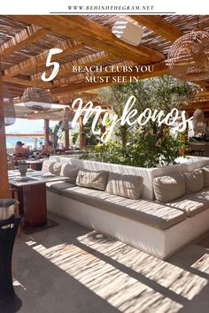 a white couch sitting under a wooden roof next to a table with chairs and umbrellas