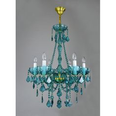 a green chandelier hanging from the ceiling with blue glass beads and gold accents