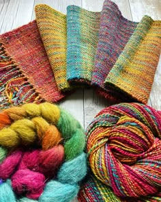 several skeins of yarn laid out on a white wooden surface with one colorful skein