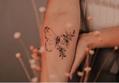 a woman's arm with a butterfly and flowers tattoo on the left side of her arm