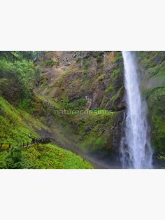 a large waterfall in the middle of a lush green valley with people standing below it