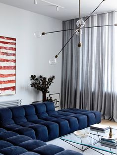 a living room filled with blue couches and a large painting hanging on the wall