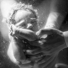 a black and white photo of a baby being held by someone's hands