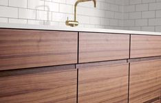 a bathroom with wooden cabinets and white tiles on the walls, along with a brass faucet