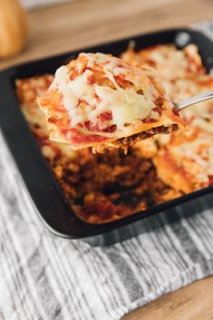 a spoon full of lasagna casserole being lifted from a baking dish