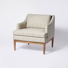 an upholstered chair with wooden legs and arm rests on a plain white background