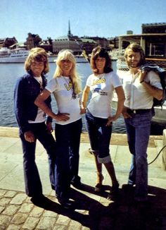 four people posing for a photo in front of the water