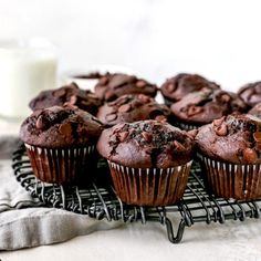 chocolate muffins on a cooling rack with a glass of milk in the background