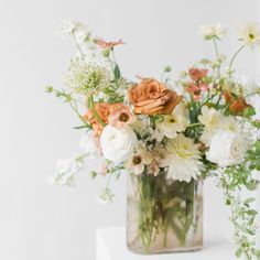 a vase filled with lots of flowers on top of a white countertop next to a wall