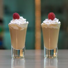 two dessert cups with whipped cream and raspberries on top