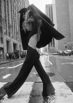 a woman walking across a street holding an umbrella