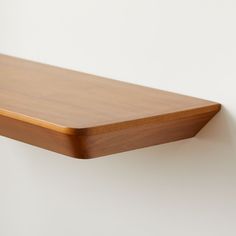 a wooden shelf mounted on the wall with a white back ground and light wood trim