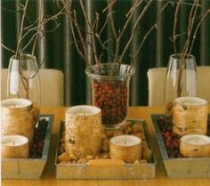 candles are placed on trays with branches and berries in the center, along with other decorations