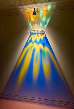 a blue and yellow vase with light coming from it